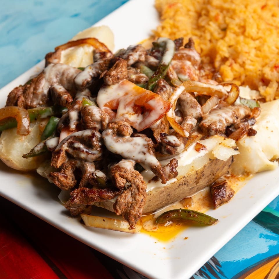 Magueys Mexican Restaurant's carne asada baked potato with rice, topped with cheese sauce.